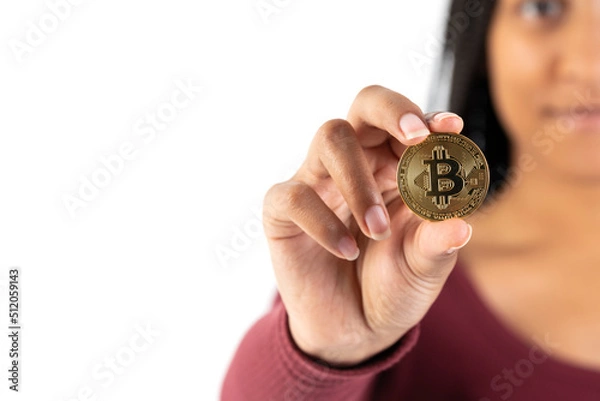 Fototapeta Young black woman showing a bitcoin coin to the camera on a white background.