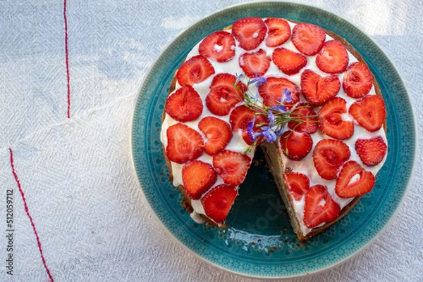 Fototapeta Cake with strawberries and cream on blue plate. Summer Strawberry and Cream sponge Layer Cake on white table cloth background. Top view, copy space. Midsummer food dessert