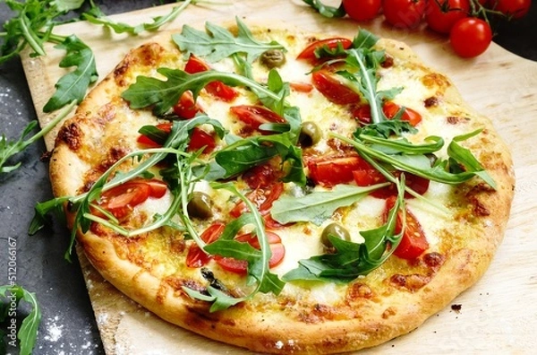 Obraz Freshly baked pizza with arugula, tomato, olive,  hollandaise sauce and mozzarella