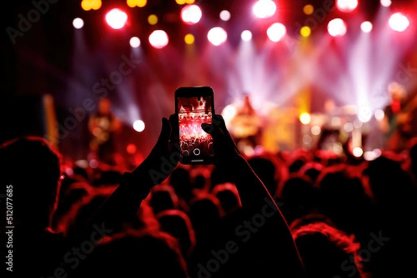 Fototapeta Streaming a music concert to social media via smartphone.