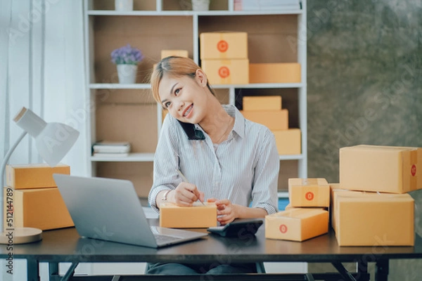 Fototapeta Looking camera, Startup small business SME, Entrepreneur owner using tablet taking receive and checking online purchase shopping order to preparing pack product box