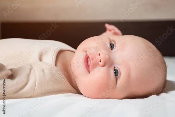 Fototapeta Adorable newborn girl with closed eyes sleeps peacefully in bed. Portrait of little baby with plump cheeks at daytime sleep in nursery, close up