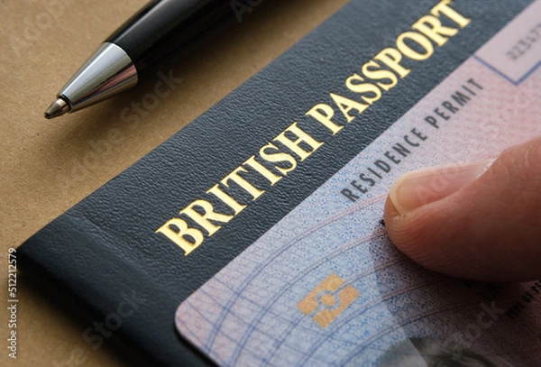 Obraz Finger pointing at Biometric Residence permit Card (ILR, Indefinite leave to Remain) placed on top of British passport. Concept for naturalization. Stafford, United Kingdom, July 20, 2022