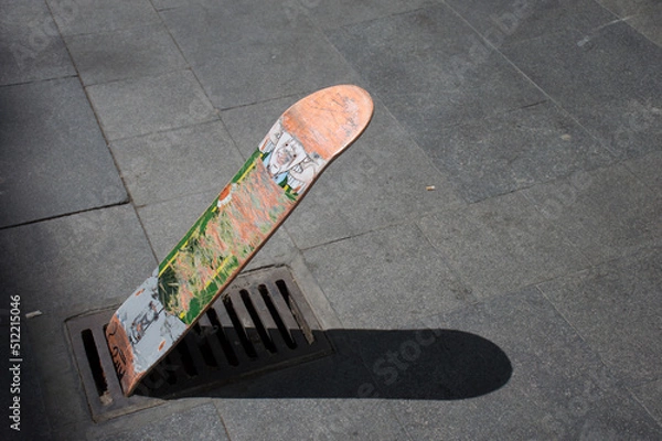 Fototapeta A skate board standing in a well or pockmark in the sidewalk or pavement