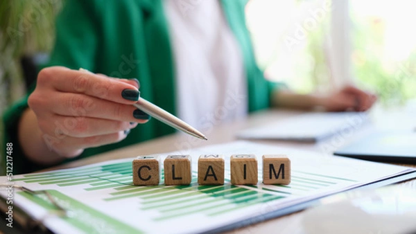 Fototapeta Woman pointing with pen on word claim made with wooden cubes in row