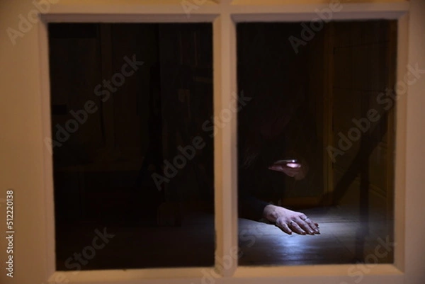 Fototapeta A scary picture of a reflection in a window of one hand in the light in a dark surrounding 