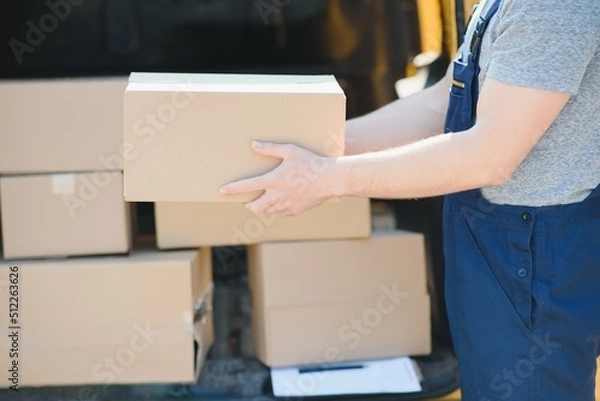 Fototapeta delivery service employee. Portrait of man working in delivery service. Portrait of courier with box. Courier next to minivan. Delivery service career.