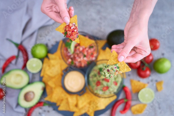 Fototapeta freshly made salsa and guacamole dip sauce with nacho chips on stone serving board