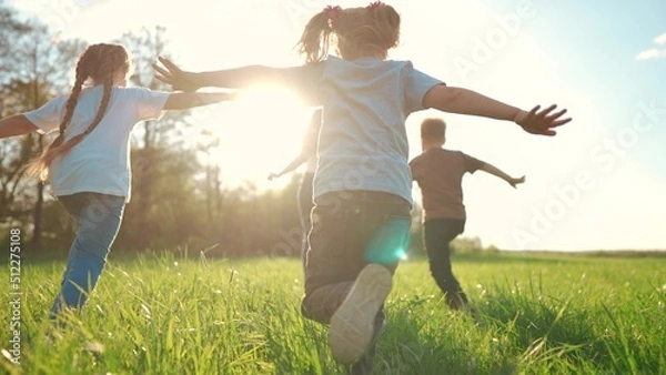 Fototapeta kids run in the park. a large group of a team of children running back view sunlight in the summer on the grass in lifestyle the park camera movement. people in the park happy family kid dream concept