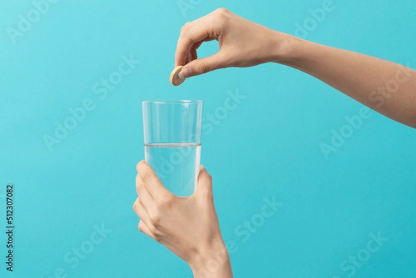 Obraz a female hand drops an effervescent tablet
