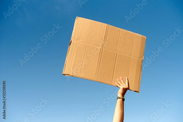 Fototapeta A cardboard Signs empty held by a hand on sky background