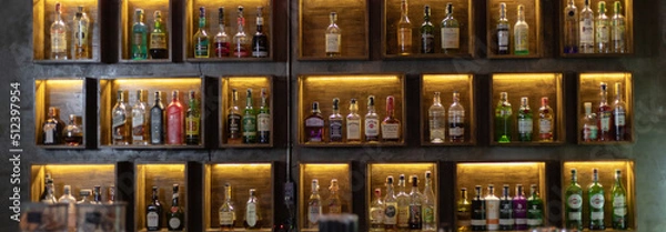 Fototapeta Wide variety of bottles of alcohol or liqueur are placed on the shelves of a vintage bar in Chiangmai, THAILAND: March 4, 2021