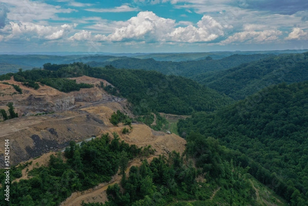 Fototapeta Green Mountain Valley with Mountaintop Mining Under Puffy Clouds and Blue Sky