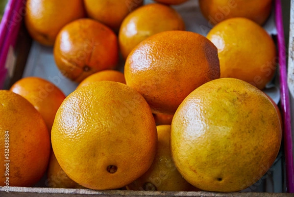Fototapeta Yellow oranges placed on a shelf for sale within a market