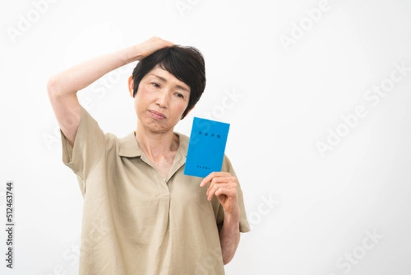 Fototapeta 年金手帳を持ちながら不安な表情をするミドル女性