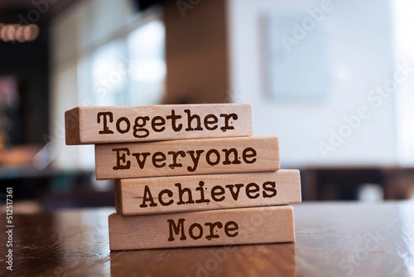 Fototapeta Wooden blocks with the word Together, Everyone, Achieves, More. Teamwork and team concept. Community, support, partnership. Achieving a common goal. Cooperation and business strategy
