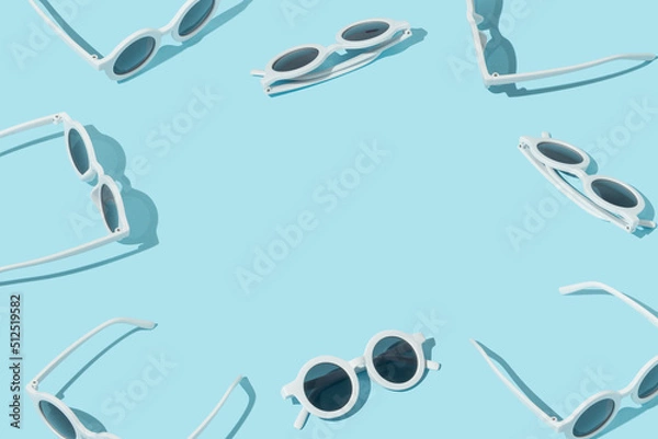 Fototapeta Summer creative pattern with white trendy sunglasses on pastel blue background. 80s or 90s retro aesthetic fun idea. Minimal summer fashion idea with copy space.