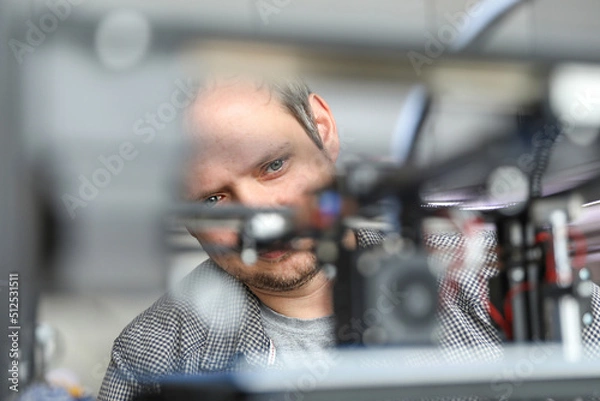 Fototapeta An engineer is setting up a machine for 3D printing, a printer for volumetric printing of parts.