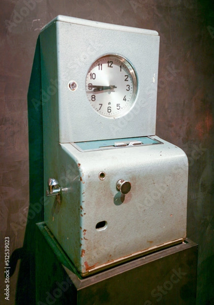 Fototapeta Vintage factory time / punch clock. A retro time clock / vintage punch clock is a device that records start and end times for hourly employees.