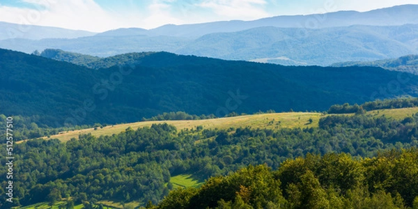 Fototapeta mountain scenery on an idyllic summer day. countryside landscape of capathian alps with fresh green meadows an forested hills. village in the distant valley. clouds on the blue sky in afternoon light