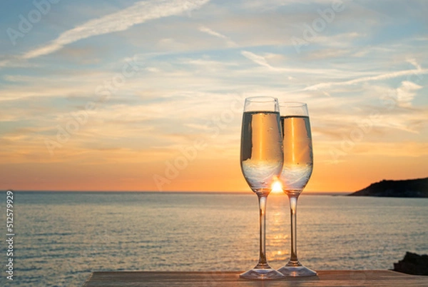 Fototapeta Pair of champagne flutes with prosecco in from of sunset in Woolacombe, North Devon, UK