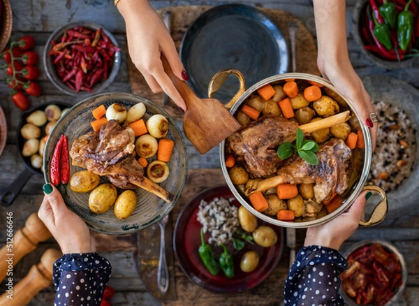 Fototapeta Cooked shank with vegetables in the cooking pot. Many foods on the table. 