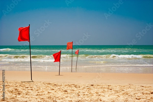 Fototapeta Swimming is dangerous in ocean waves. Red warning flag flapping