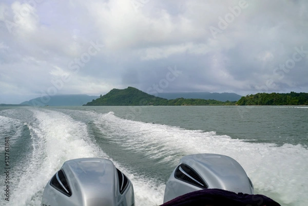 Fototapeta Water waves and white sponges formed by boat propellers. Behind is the sea and beautiful islands.