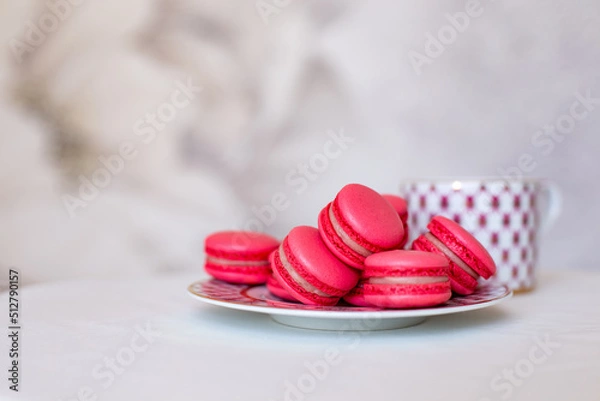 Fototapeta Sweet pink macaroons on the table next to a classic cup of tea. Vintage tea party. 5 o'clock. Sweets and pastries, desserts with their own hands. Handmade