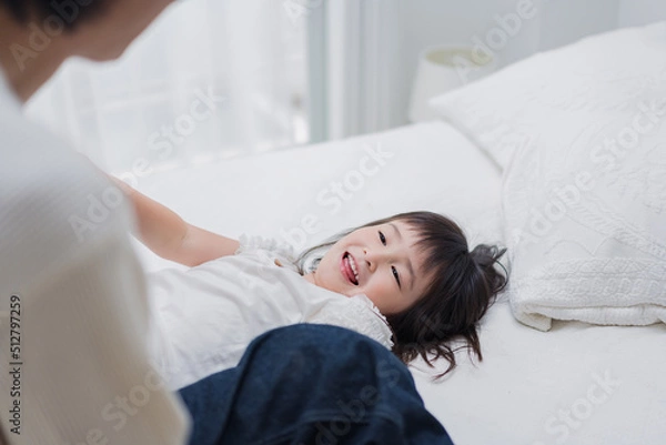 Fototapeta パパと一緒にベッドで遊ぶ小さな女の子