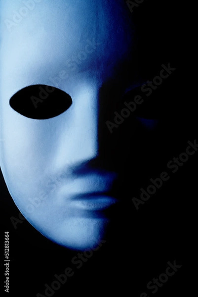 Fototapeta Close up image of creepy and scary mask face. White mask falls off into shadow on right side of frame. Halloween scary costume concept. Copy space