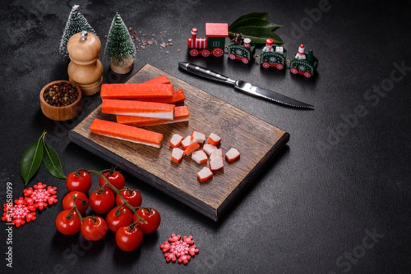 Fototapeta Crab sticks on a cutting Board with a knife. On a black christmas table