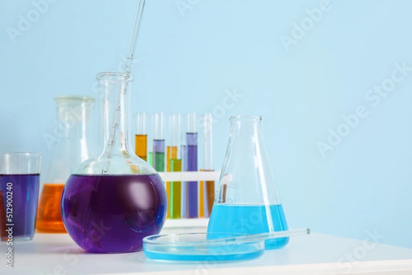 Fototapeta Different laboratory glassware with samples on table near blue wall