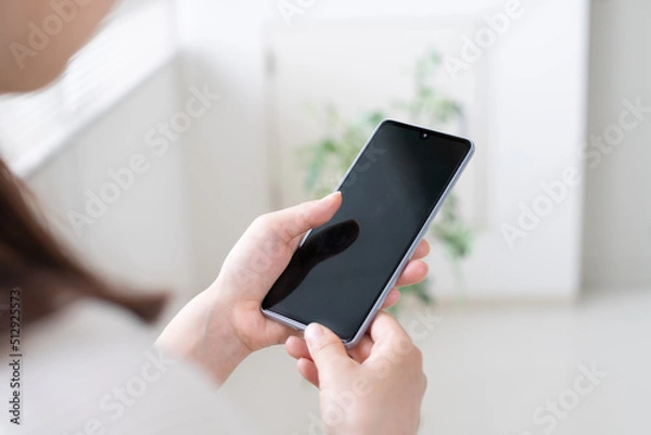 Obraz スマホやSNS運用をする女性の手元