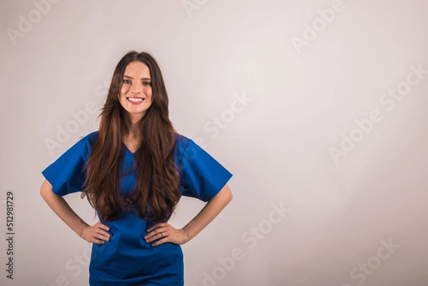 Fototapeta portrait of nurse in blue uniform looking at camera on light studio background