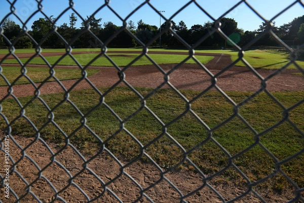Fototapeta A baseball field shot through the fence in the early morning.