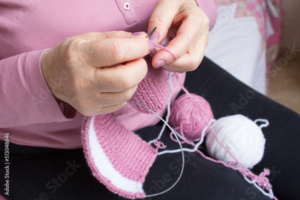 Obraz Process of yarn knitting by elderey woman: arms, spins, thread - close up