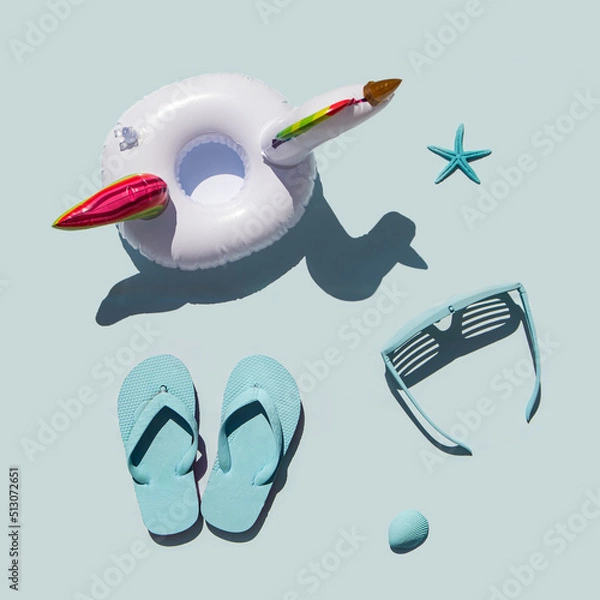 Fototapeta Minimalistic beach concept. Sea symbols idea. Sunglasses, flip flops, starfishes and seashell on pastel blue background. Creative summer concept. Holiday composition. Flat lay.