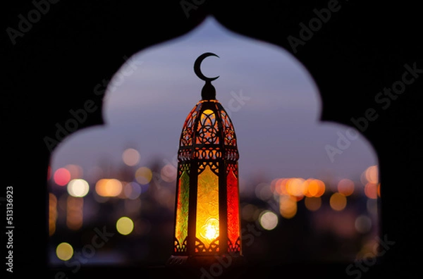 Fototapeta Lantern that have moon symbol on top with blurred focus of paper cut for mosque shape background. Ramadan Kareem and Islamic new year concept.