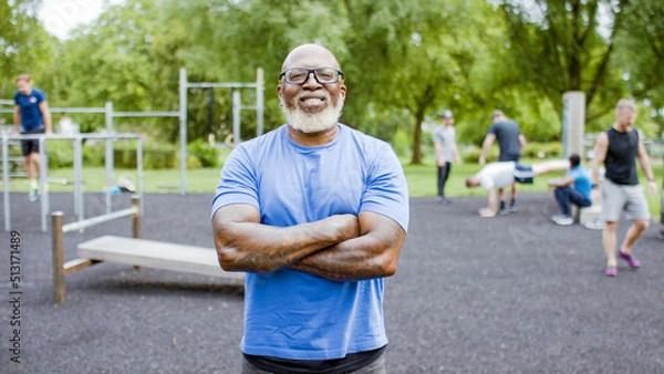 Fototapeta Portrait of confident, muscular black senior man with his arms folded smiling to camera