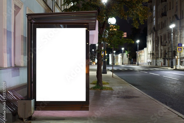 Fototapeta Empty billboard at the bus stop, night city lights. Cozy well-lit street. Mock-up.