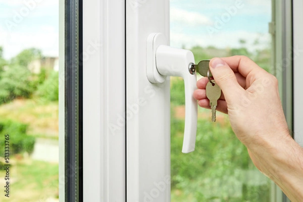 Fototapeta A man locks or unlocks a plastic window with keys