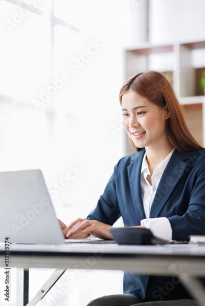 Fototapeta Asian Business woman using calculator and laptop for doing math finance on an office desk, tax, report, accounting, statistics, and analytical research concept