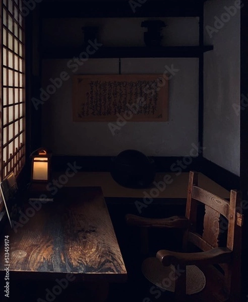 Obraz 窓から差し込む光に照らされるレトロな木製の机とイス
