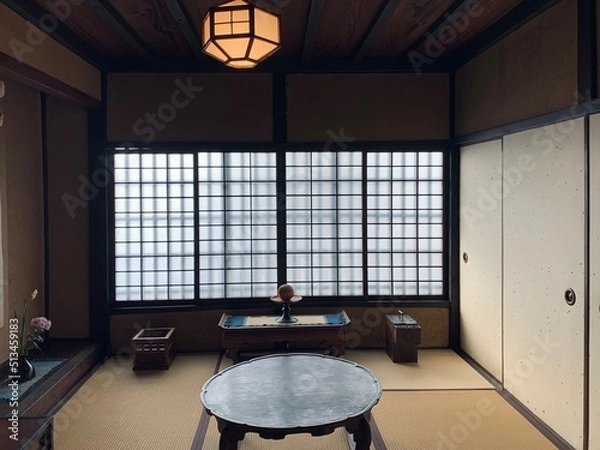 Obraz 伝統的な日本家屋の和室に置かれた机と障子の窓