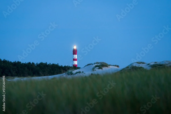 Fototapeta Lighted lighthouse on the dunes of Amrum island Germany with clear blue sky after sunset