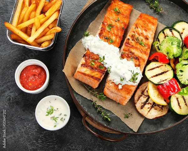 Obraz Salmon steak with vegetables on dark background.