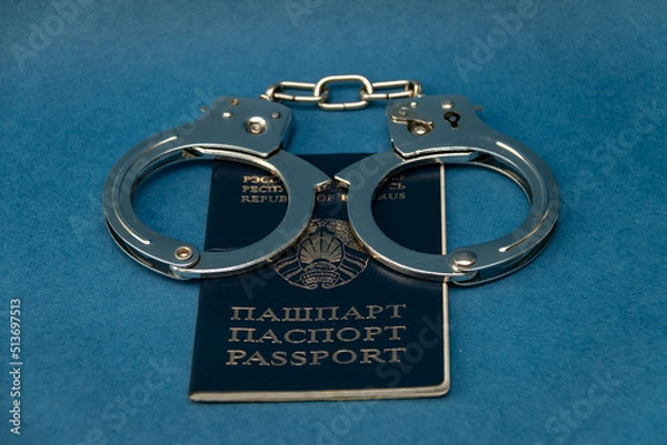 Obraz Belarusian passport and handcuffs on a blue background. The concept of illegal detentions and arrests, trials of demonstrators, political repressions against the opposition.