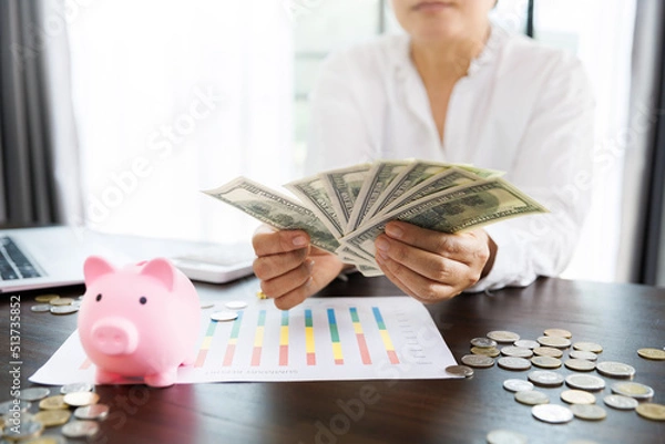 Obraz pig piggy bank on the table and women holding dollar bill for save money, saving money or savings concept.