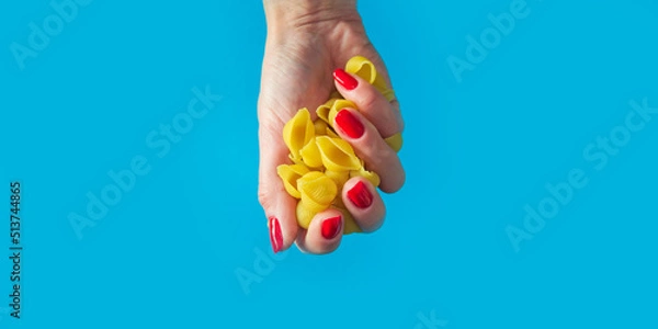 Fototapeta pasta Conchiglie in a female hand. high calorie food. calorie product. extra calories. Banner for insertion into site. Place for text cope space. Horizontal image.